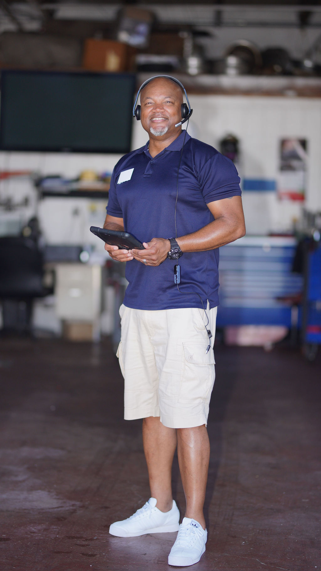 aLex Adviser standing in garage with headset and tablet, ready to help review used cars